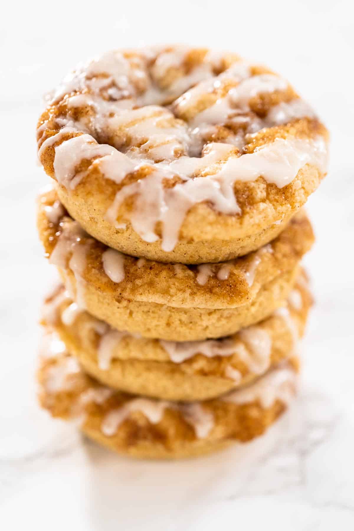 A stack of 4 cinnamon roll donuts with frosting.