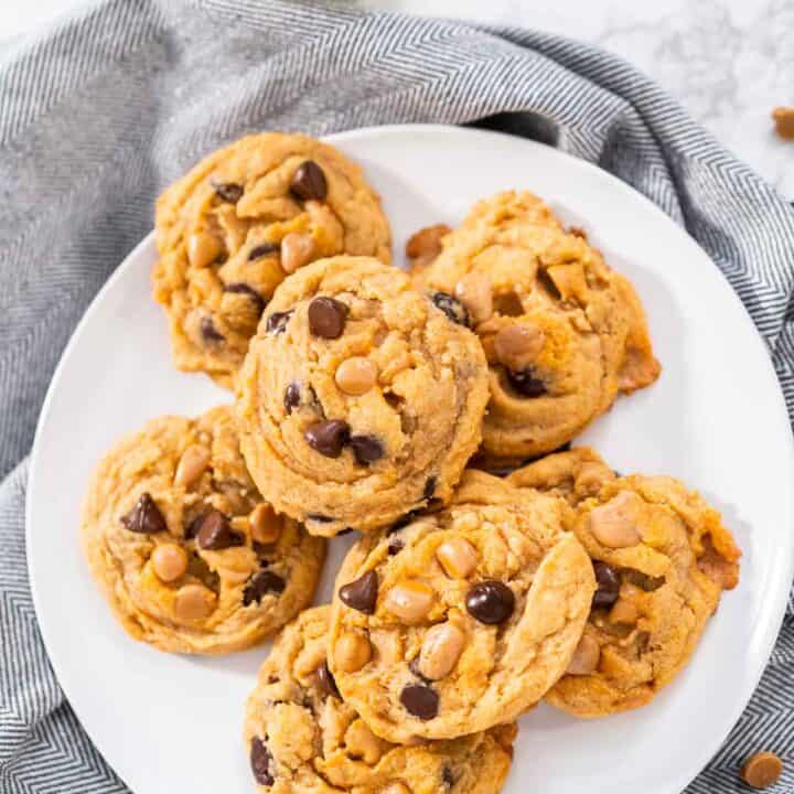 Chocolate chip butterscotch cookies on a white plate with a gray napkin.
