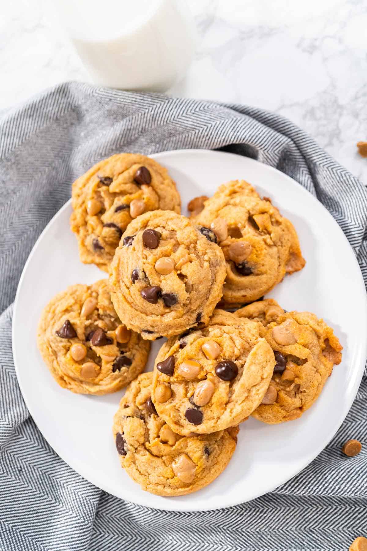 Chocolate chip butterscotch cookies on a white plate with a gray napkin.