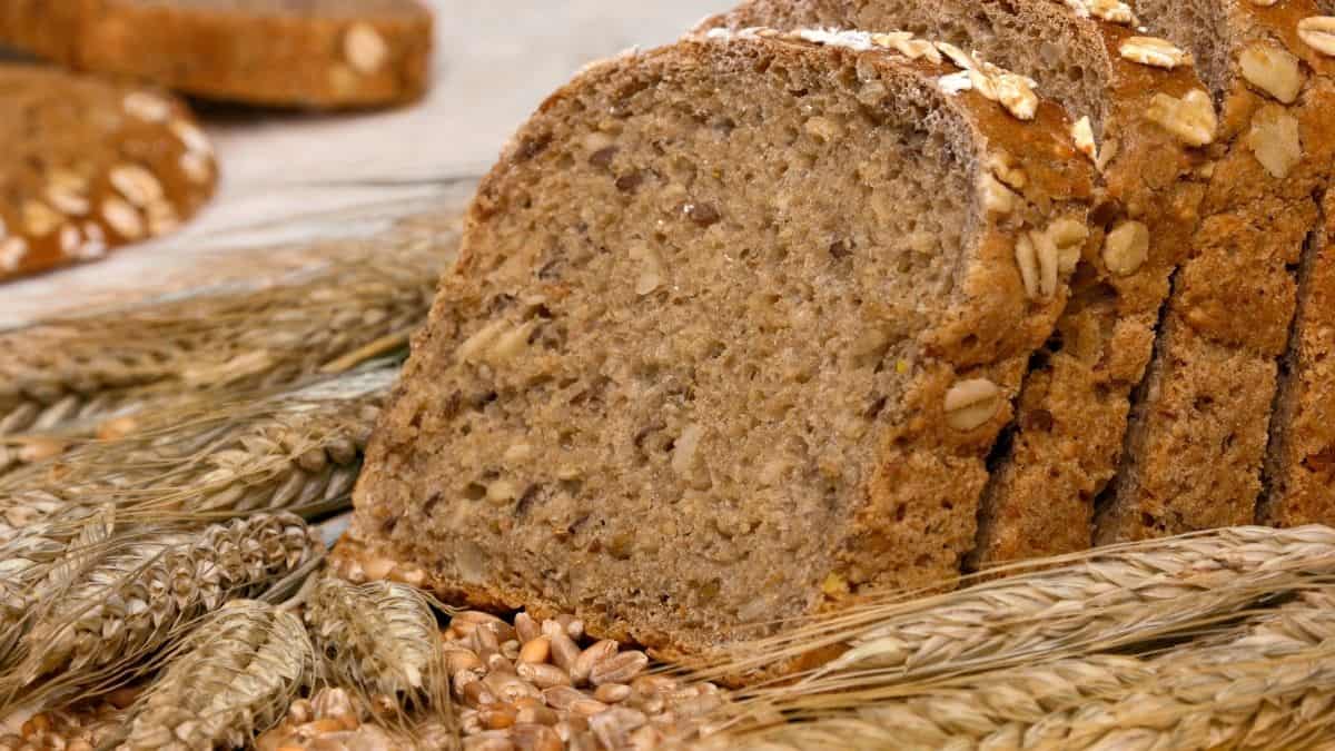 a loaf of whole grain bread surrounded by wheat, an example of a smart carb.