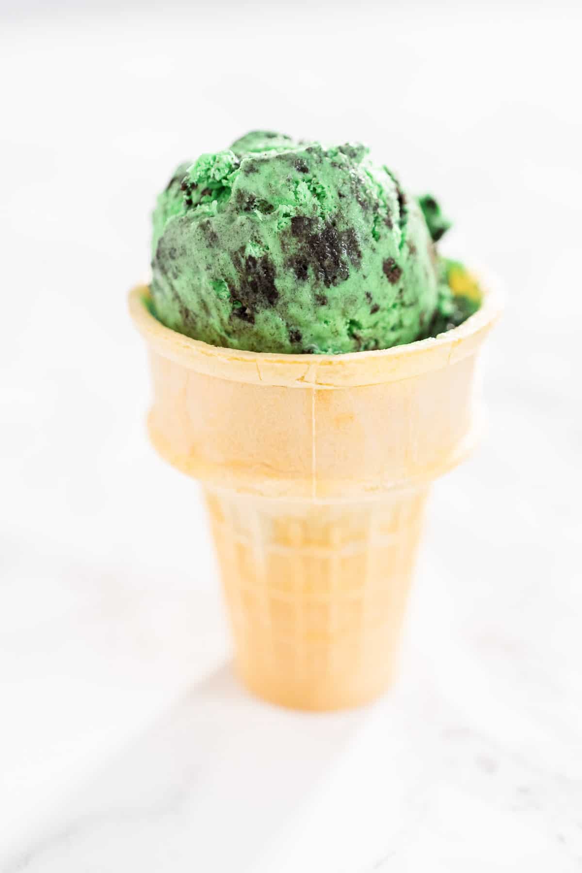 grasshopper ice cream in a cone sitting on the counter.