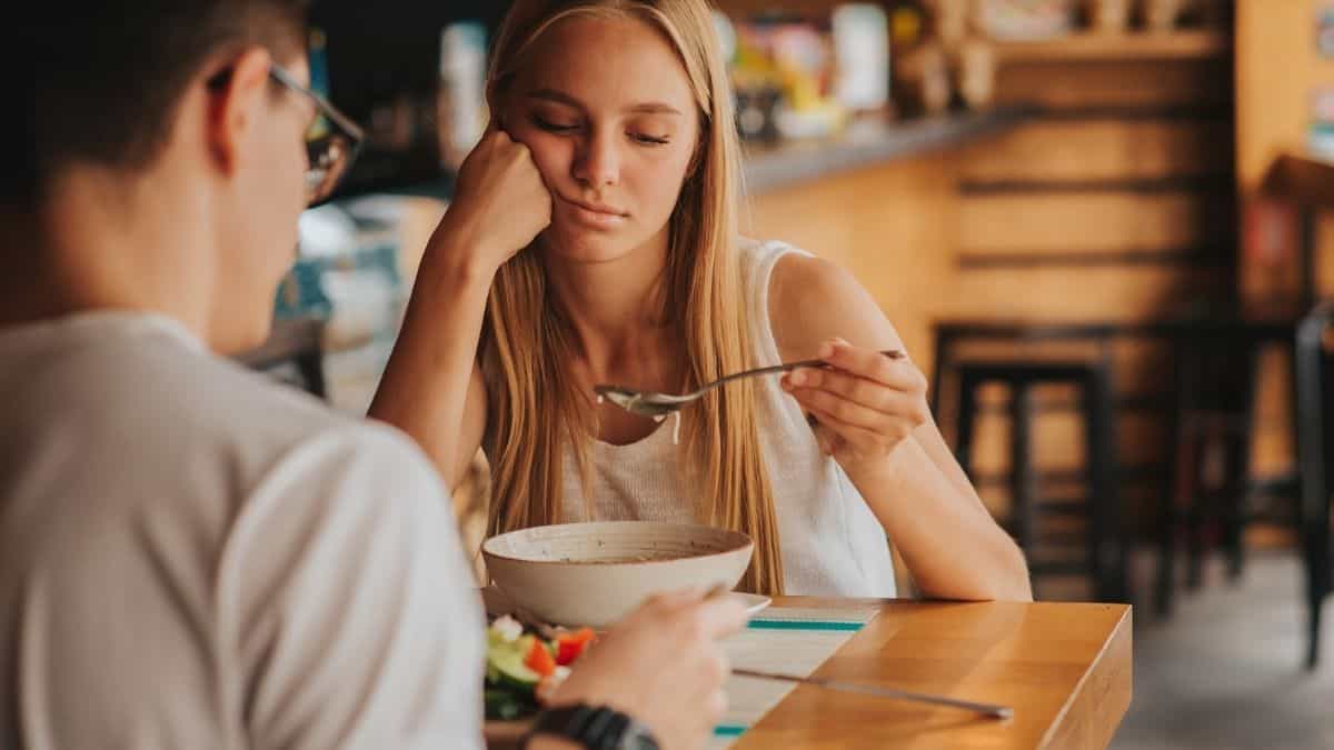 A blonde woman staring at a spoonful of soup, not wanting to eat - low appetite is a sign of anxiety.