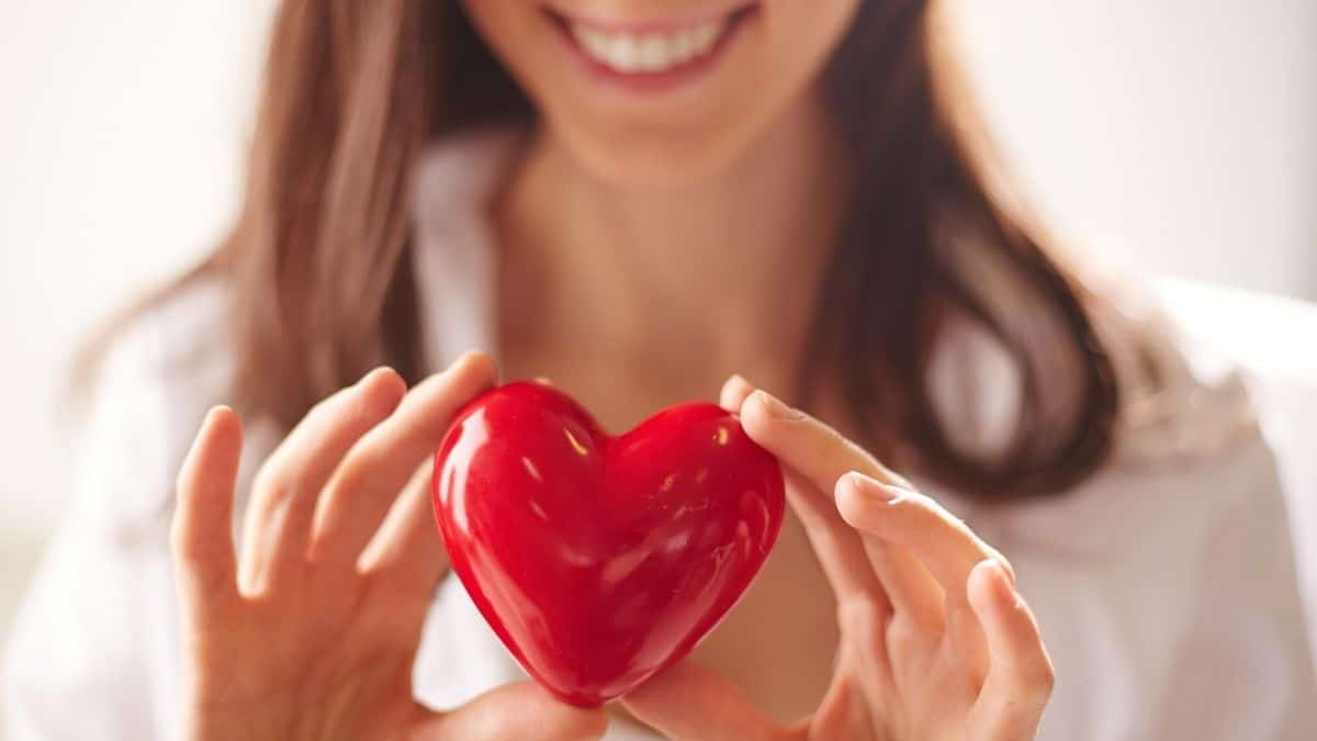 A brunette woman holding a red heart.