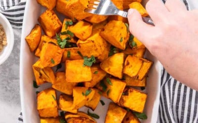A plate of sweet potato cubes, being pierced with a fork.