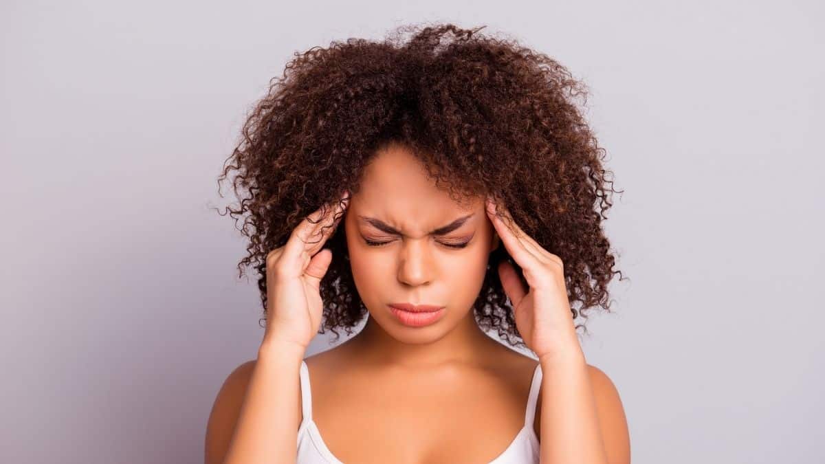 A woman with a headache - a sign of hunger - rubbing her temples.