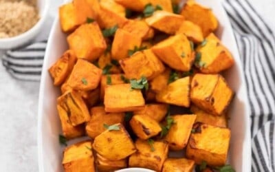 A plate of sweet potato cubes with a dipping sauce on the side.