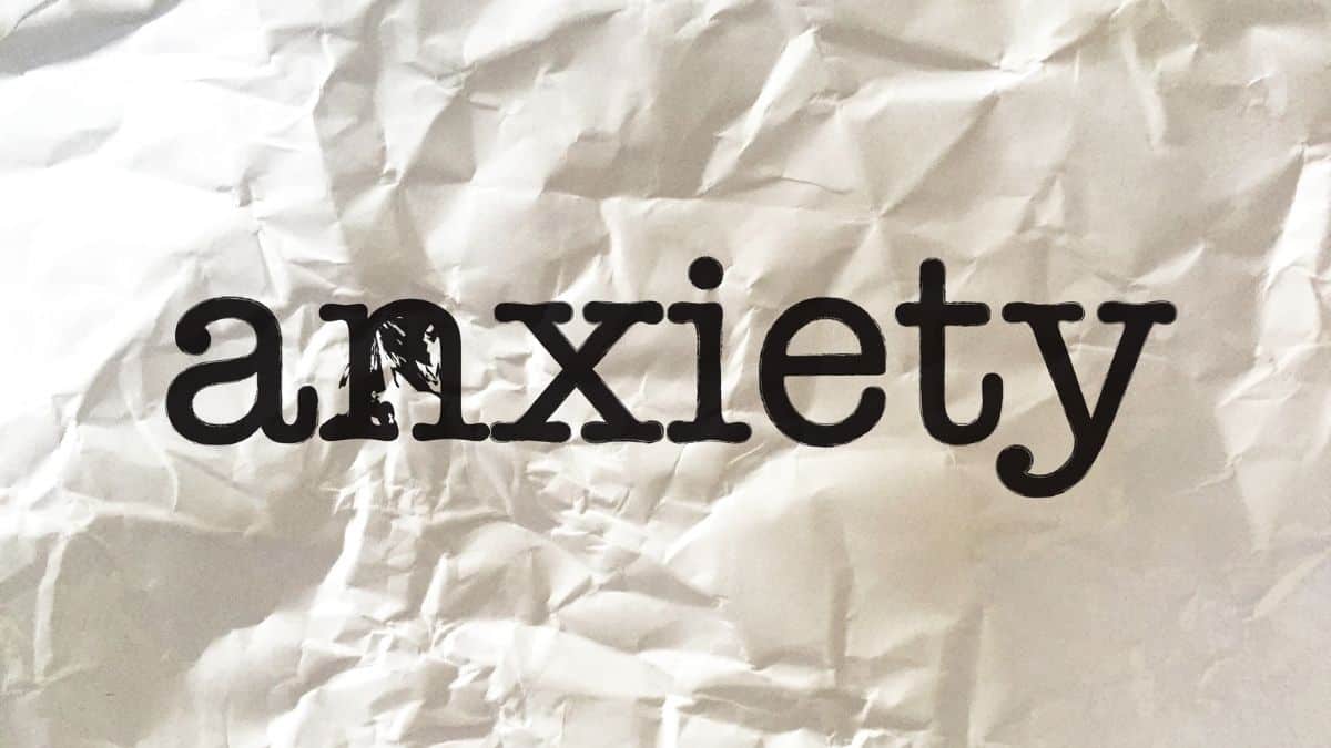 The word anxiety spelled out in black letters on a piece of white crinkled paper.