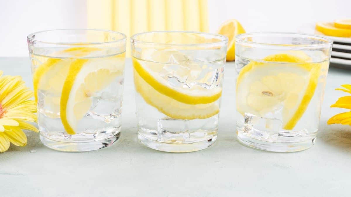 three glasses of lemon water on a table.