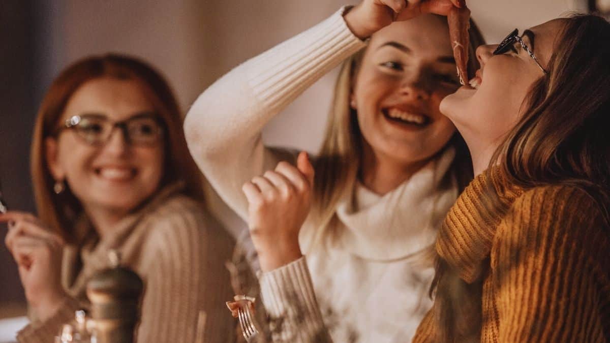 three women sitting and enjoying a meal together with smiles on their faces, a glimpse at how to combat diet culture.