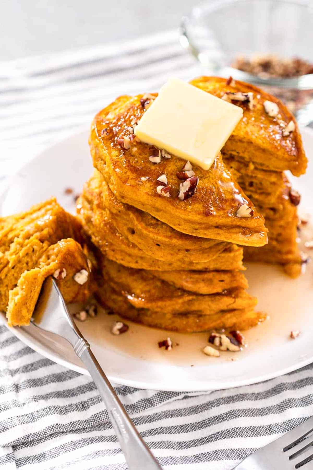 A stack of Bisquick Pumpkin Pancakes with a metal fork taking a bite out.