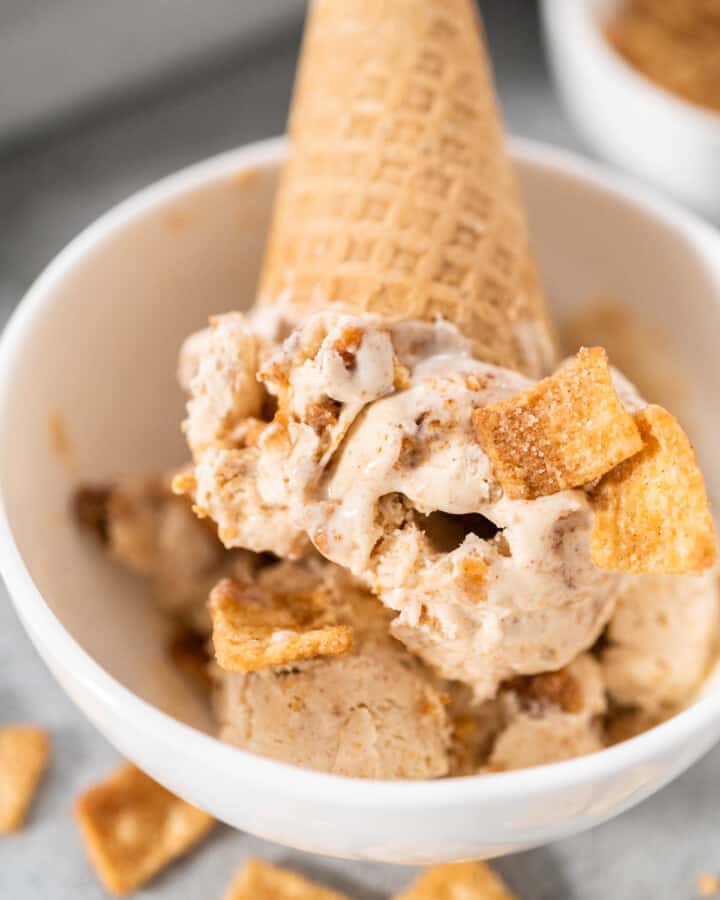A waffle cone of No Churn Cinnamon Toast Crunch Ice Cream in a white bowl.