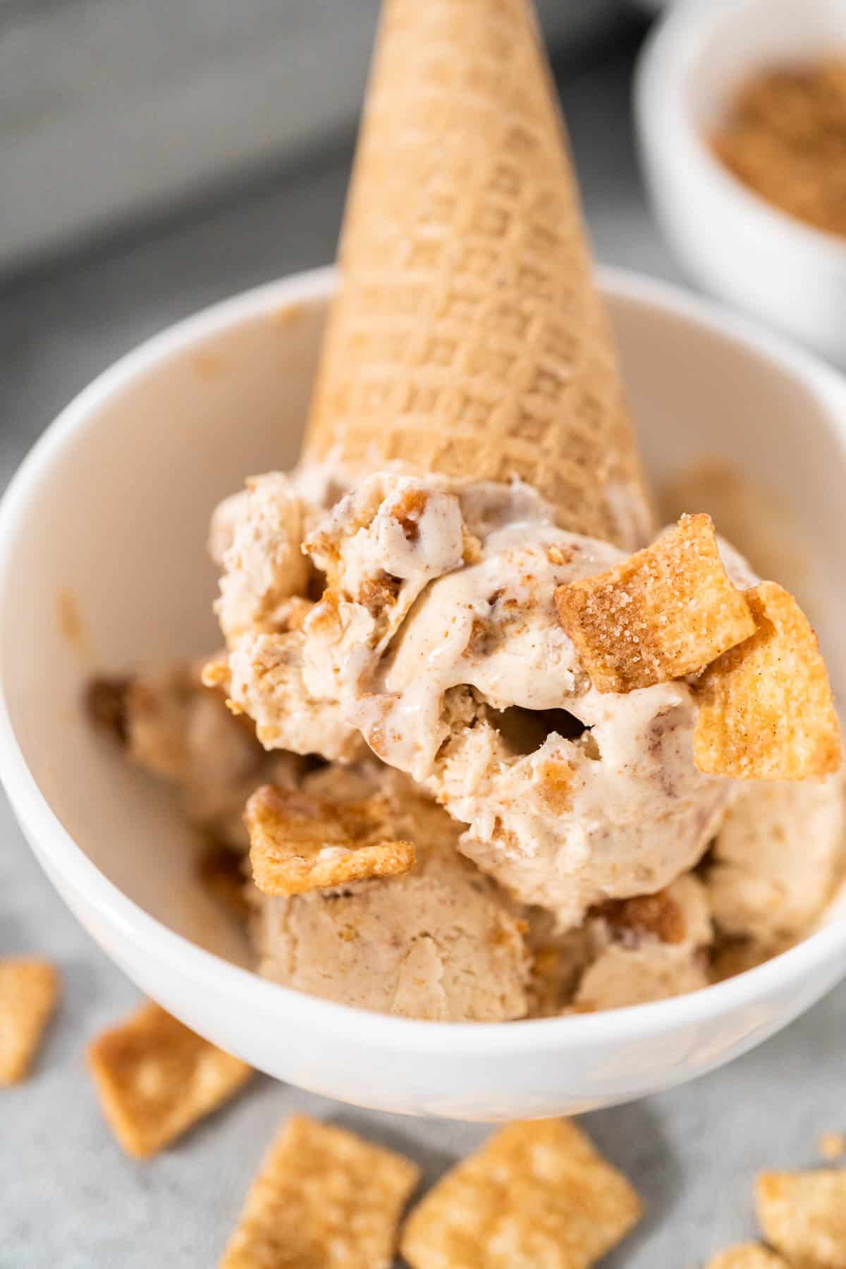 A waffle cone of No Churn Cinnamon Toast Crunch Ice Cream in a white bowl.