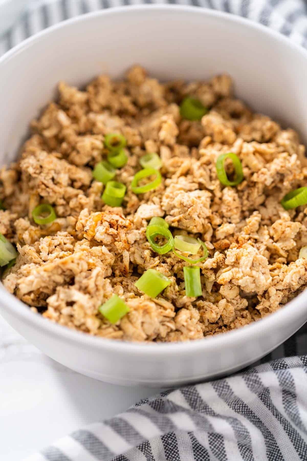 Tofu ground beef served in a white bowl with green onions on top.