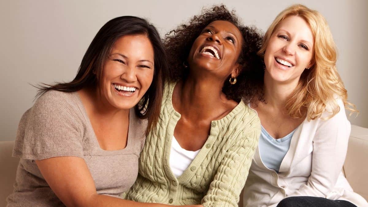 a group of three women laughing together.