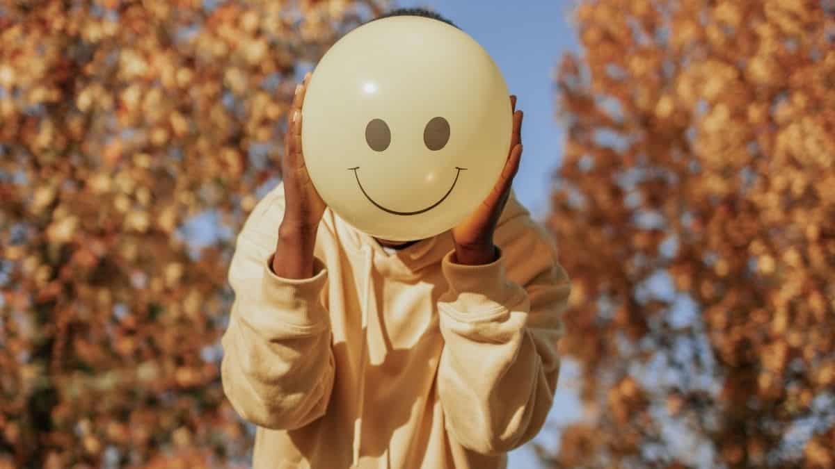 a person holding a smiley balloon in front of their face.