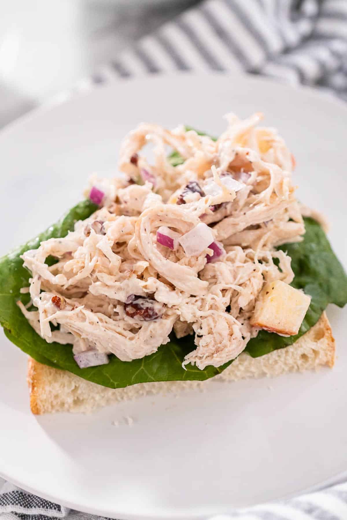A half sandwich of Apple pecan chicken salad on white bread and lettuce.