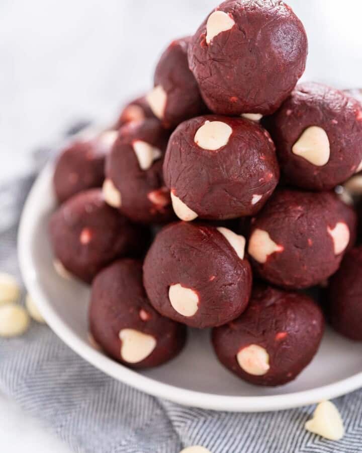 A pile of red velvet cookie dough bites on a white plate.