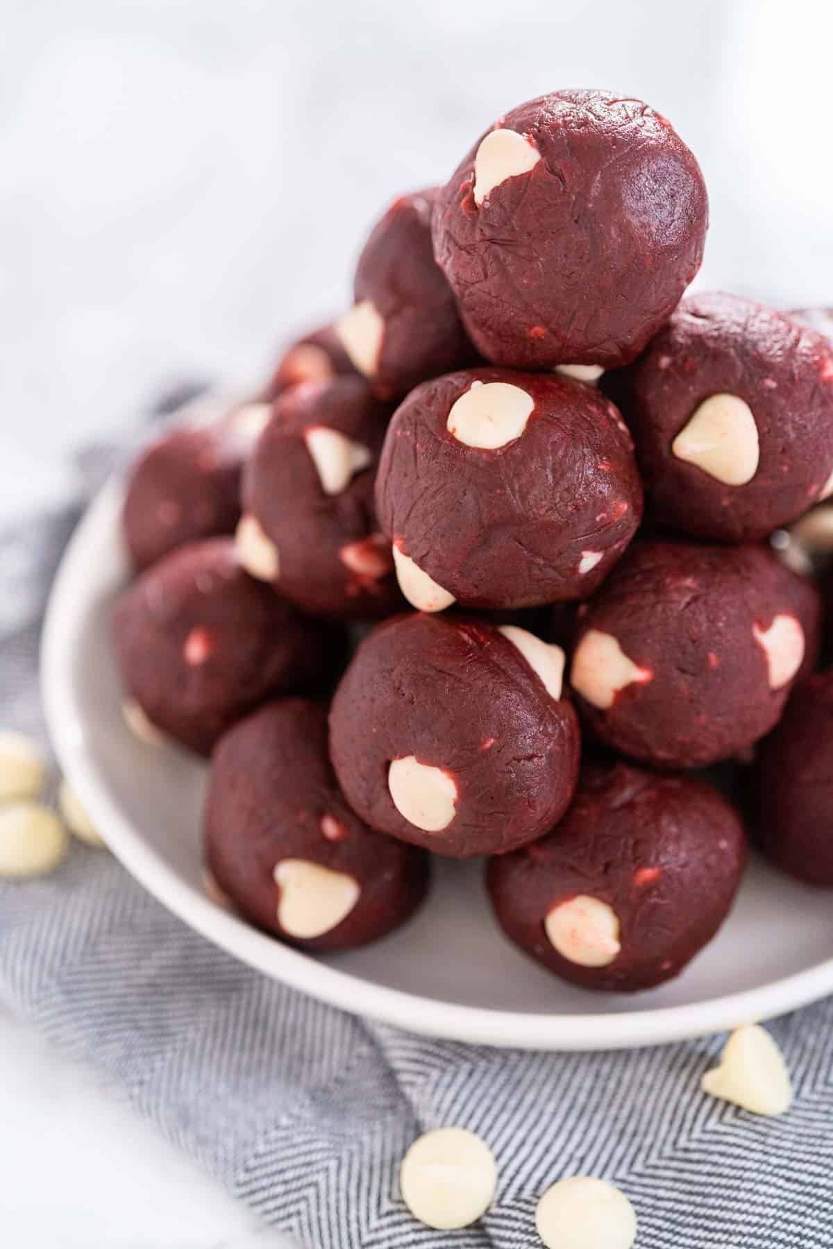 A pile of red velvet cookie dough bites on a white plate.