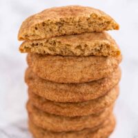 A stack of snickerdoodle cookies with the top cookie split in half to show texture.
