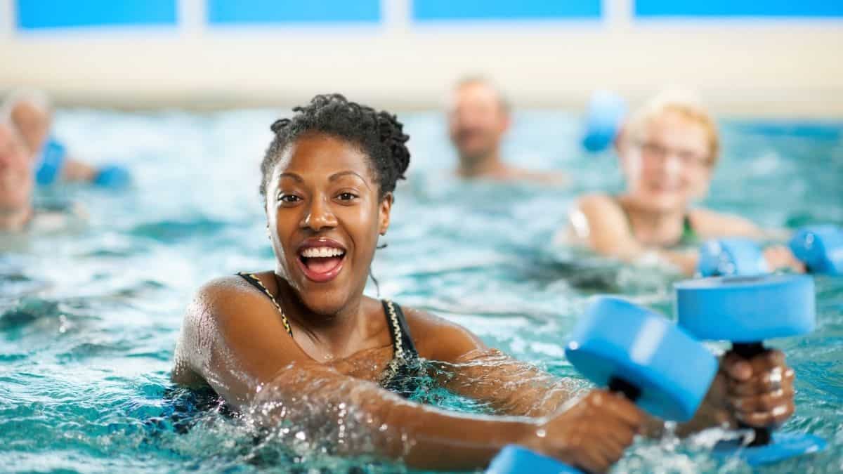 A woman in a water aerobics class with a big smile on her face, an example of joyful movement all about intuitive eating.