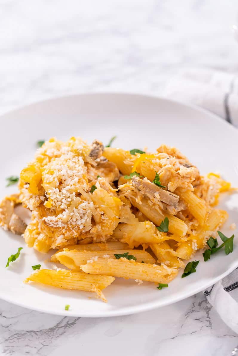 Buffalo chicken pasta bake on a white plate with herbs sprinkled on top.