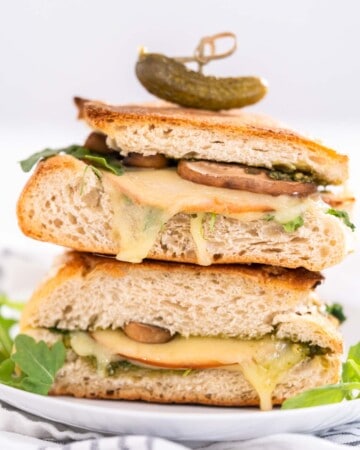Toasted Pesto Turkey sandwich on a white ceramic plate on a white and grey towel.
