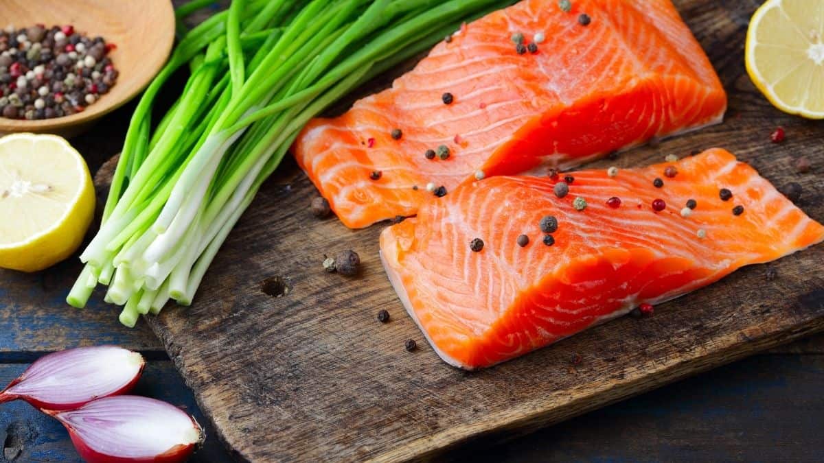 two fresh fillets of salmon on a cutting board, eating salmon is a natural way to increase fertility.