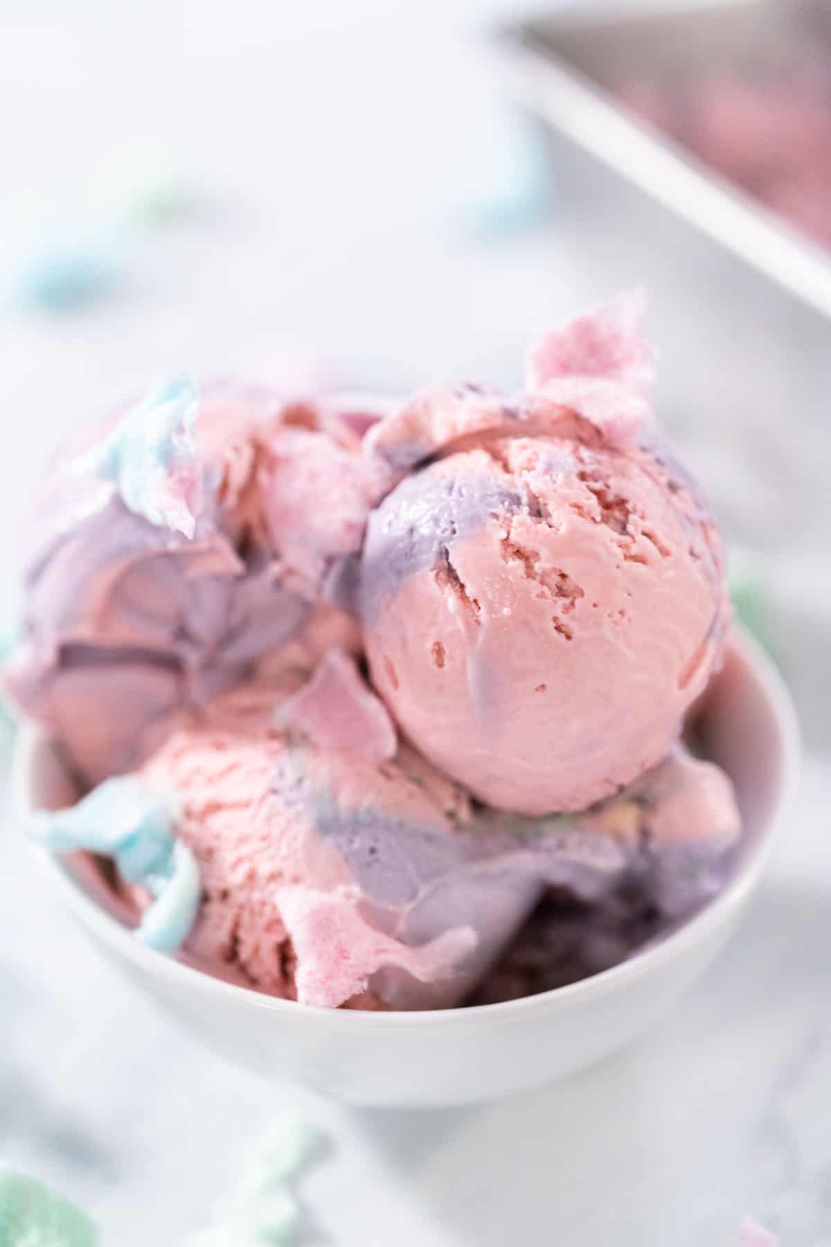 A bowl of pink and purple no churn cotton candy ice cream.