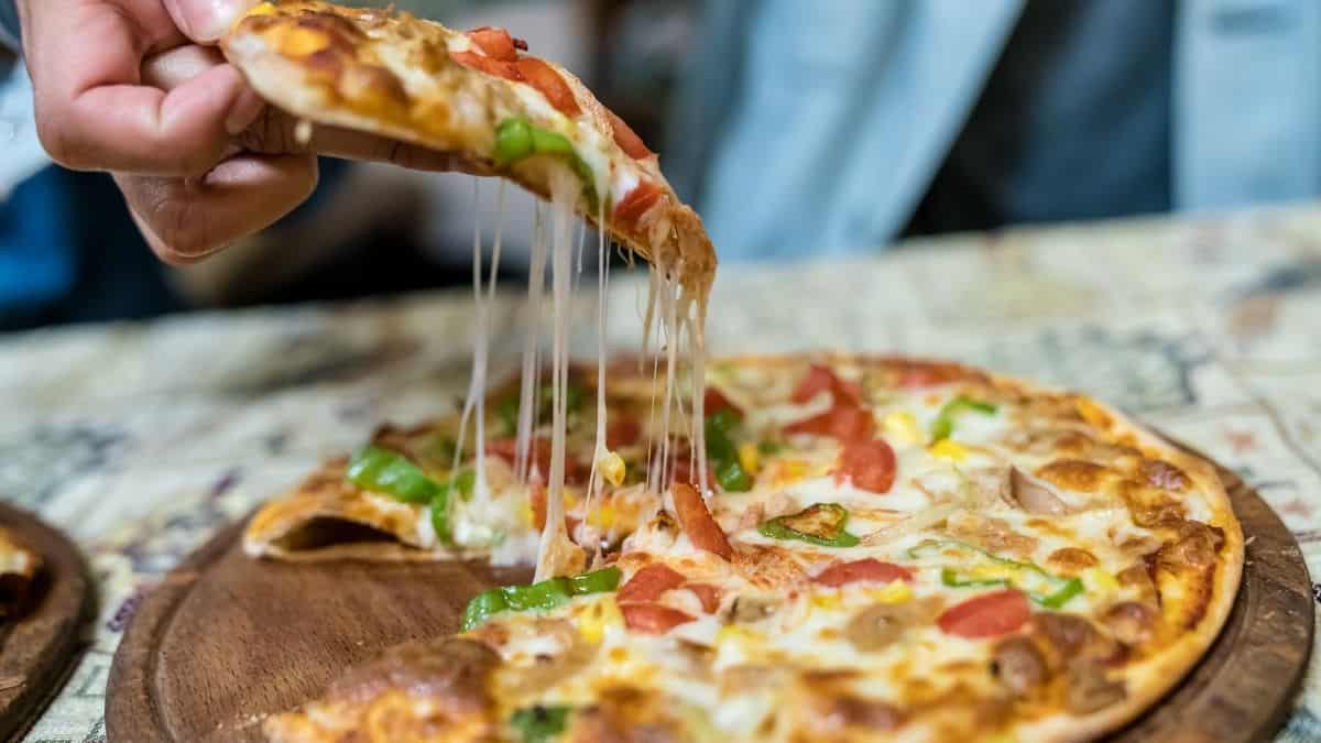 A pizza topped with vegetables on a wooden cutting board. Pizza may be a food that someone suffering from binge eating disorder may struggle with.