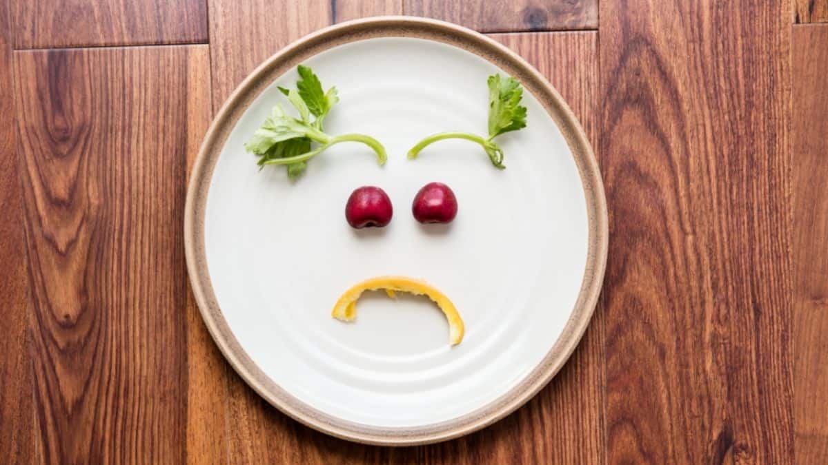 A white plate with a sad face drawn on it with food.