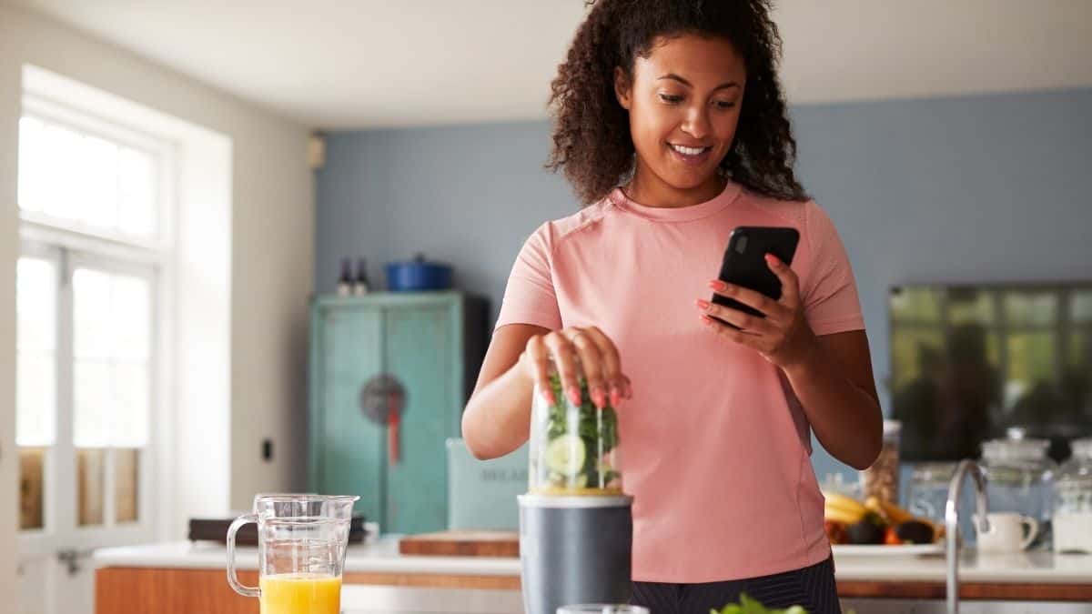 A woman holding up her phone, ready to track her latest meal on an app, maybe noom or myfitnesspal.