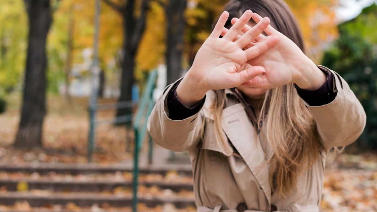 A woman with light brown hair holding up her hands to signal stop.