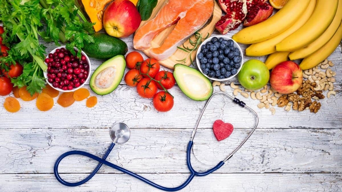 An array of healthy foods on a wooden back drop with a stethoscope.