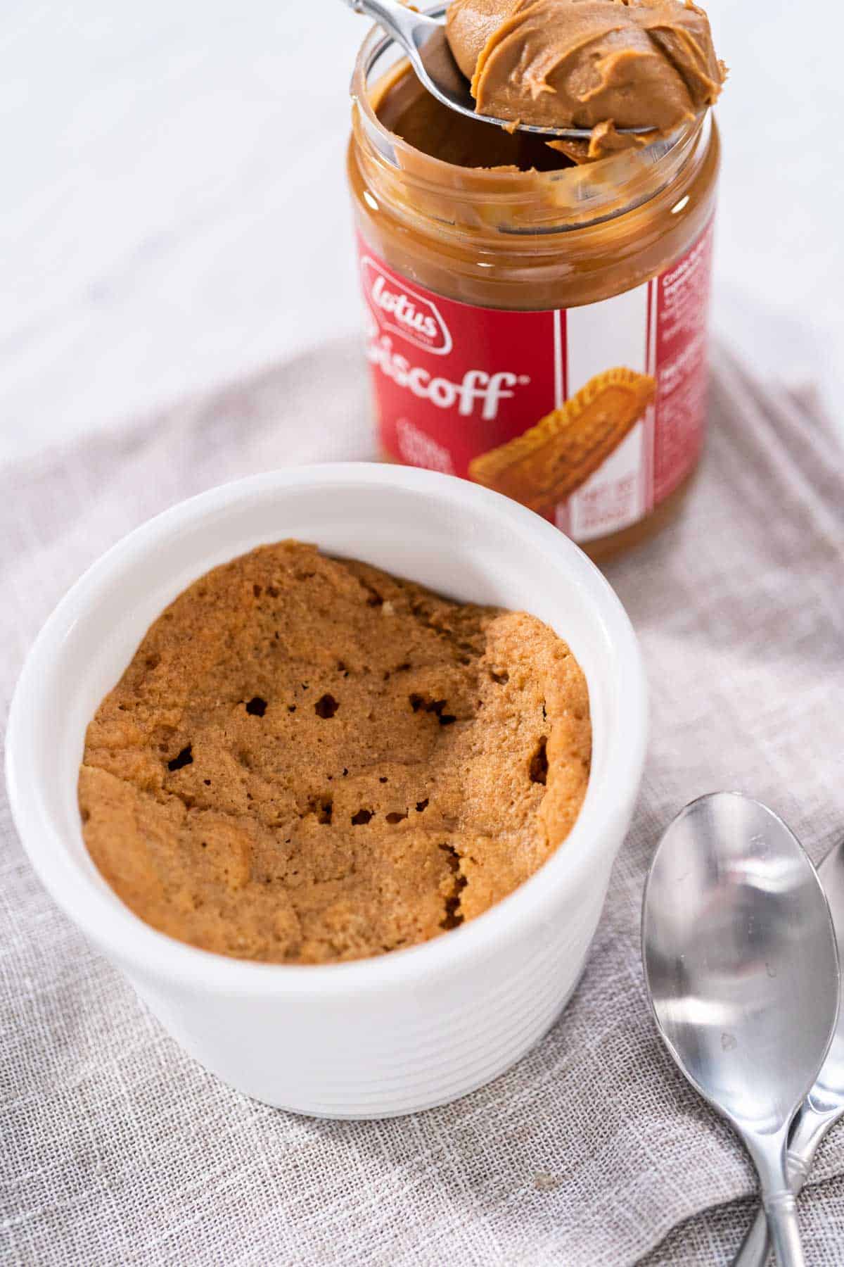 Biscoff Mug Cake in a white ramekin with a metal spoon beside the cake.