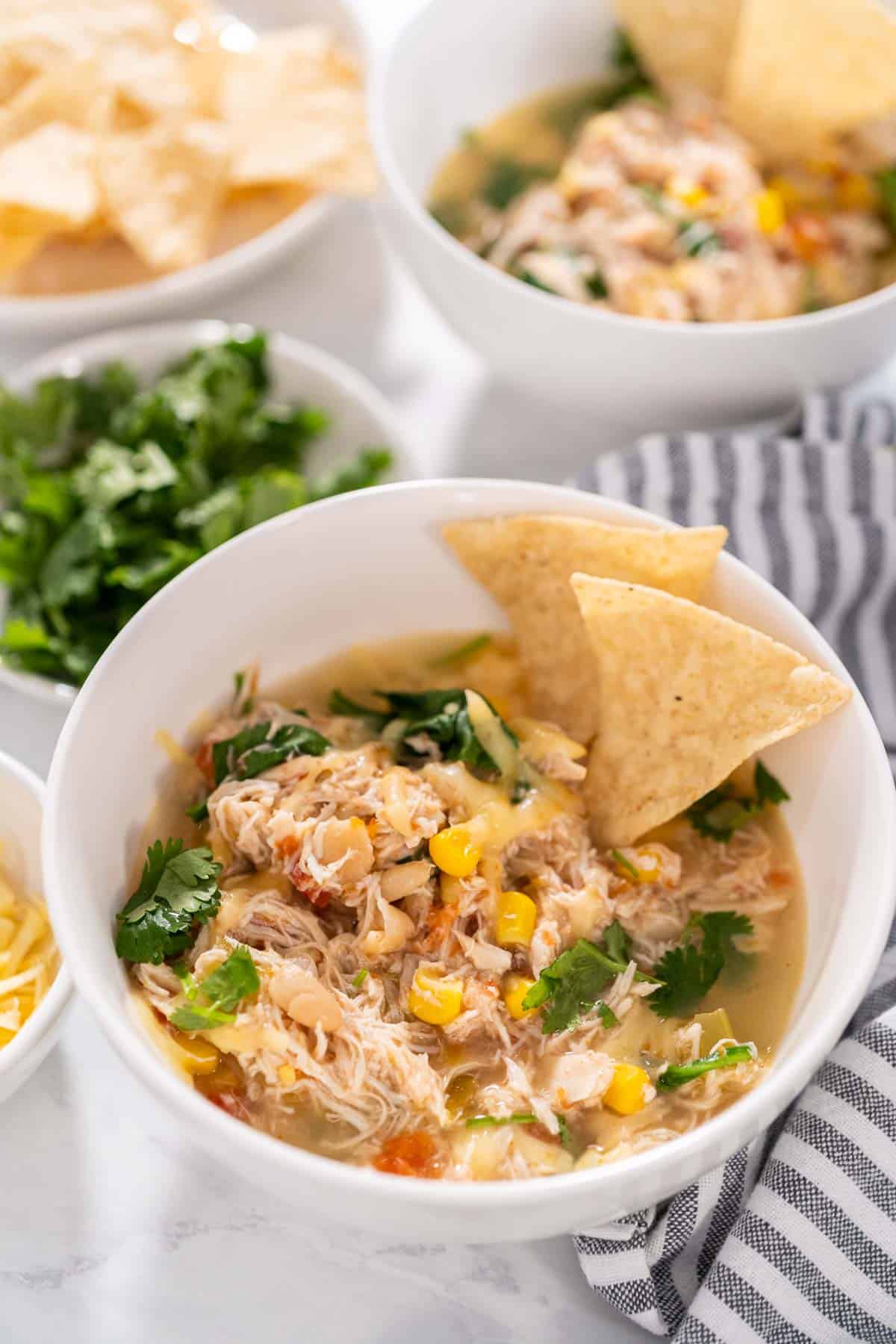Overhead shot of instant pot white bean chicken chili with two tortilla chips and ingredients surrounding bowl.