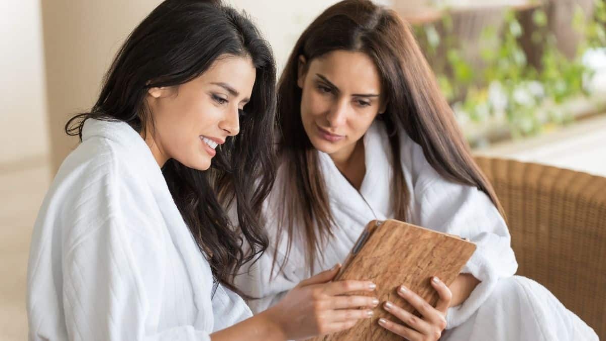 Two women looking at a tablet screen together, possibly tracking calories in noom or myfitnesspal.