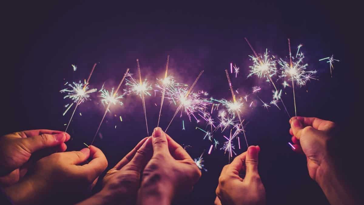 three people holding sparklers at night.