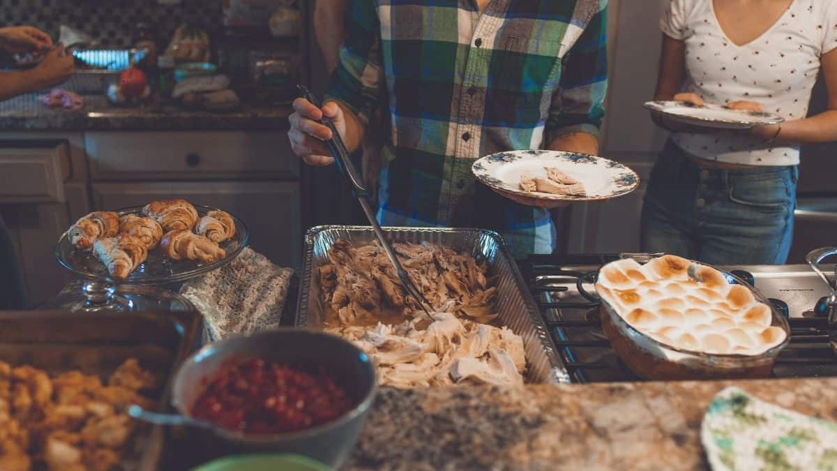 a couple serving themselves thanksgiving dinner.