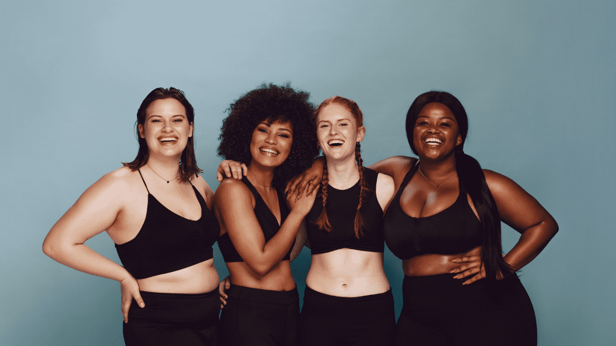 four women of different races standing together, showing all different body types.