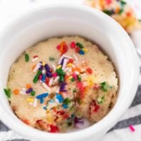 vanilla vegan mug cake in a white ramekin with a spoonful missing.