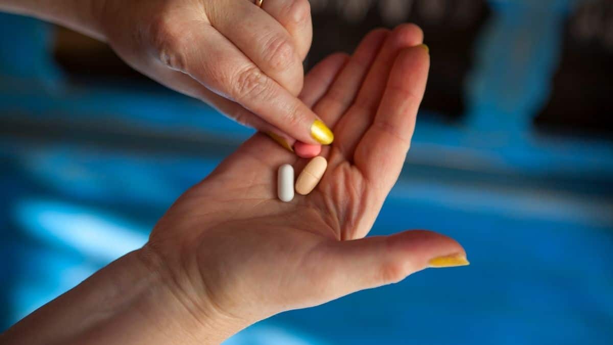 a person holding out hand with three pills in it.