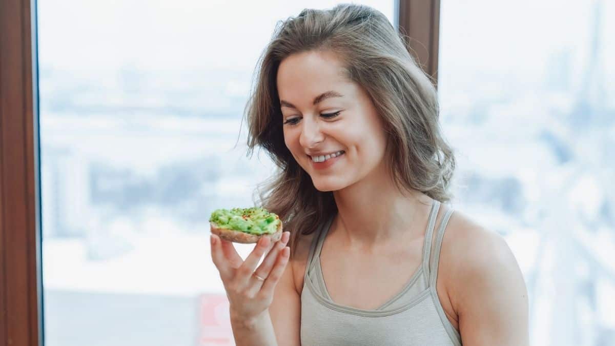 a smiling woman enjoy avocado toast.