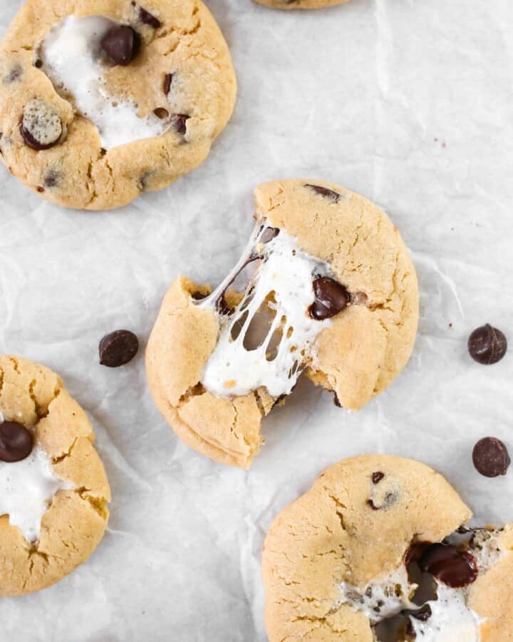 Chocolate chip marshmallow cookies on parchment paper torn in half.