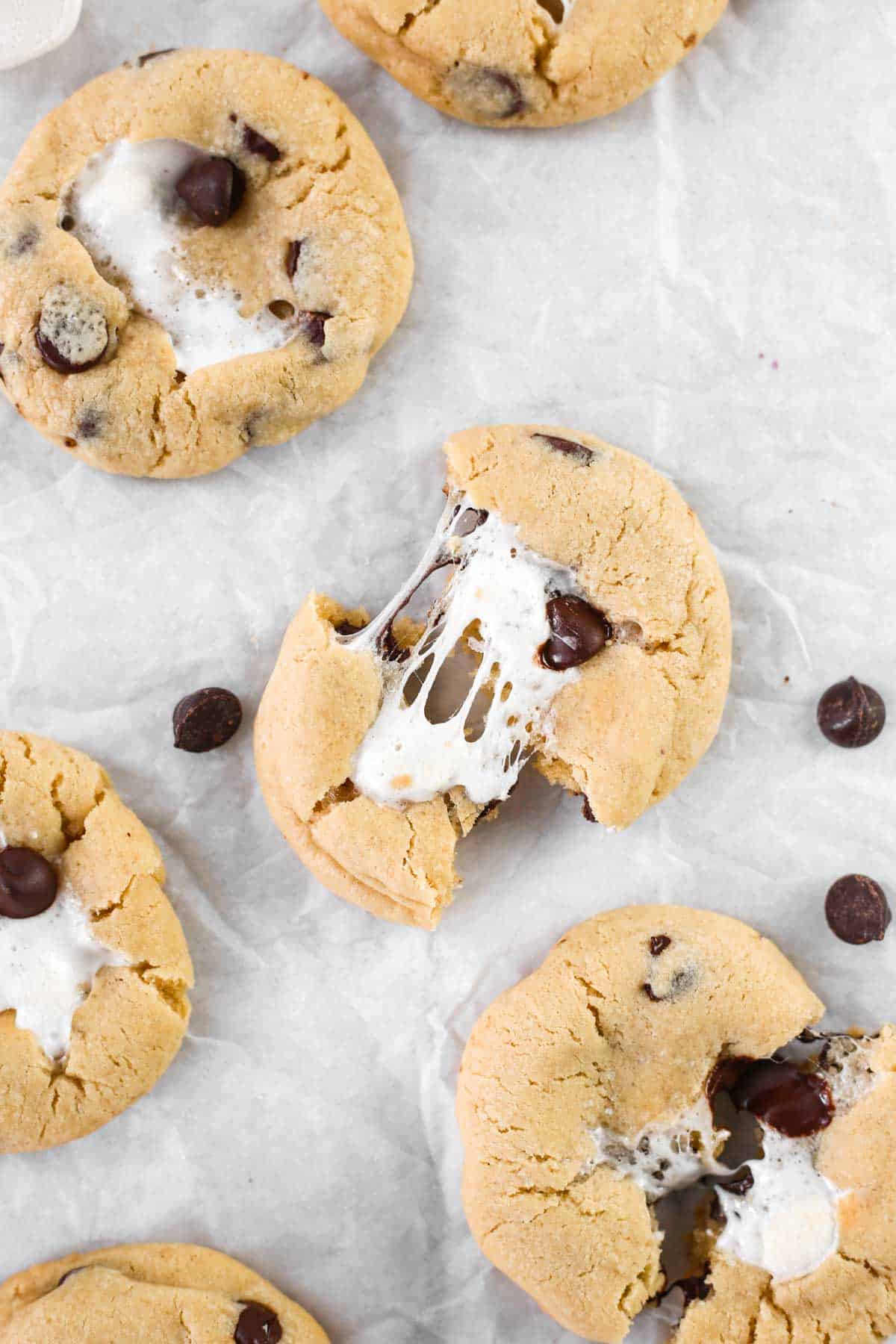 Chocolate chip marshmallow cookies on parchment paper torn in half.