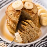 Maple syrup and bananas topping a stack of three ingredient banana oat pancakes.