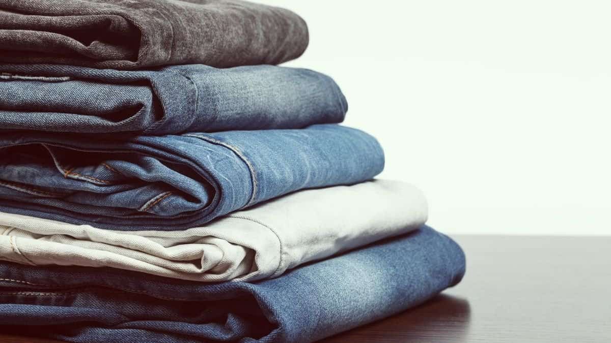 a stack of folded blue jeans at a store in a range of sizes.