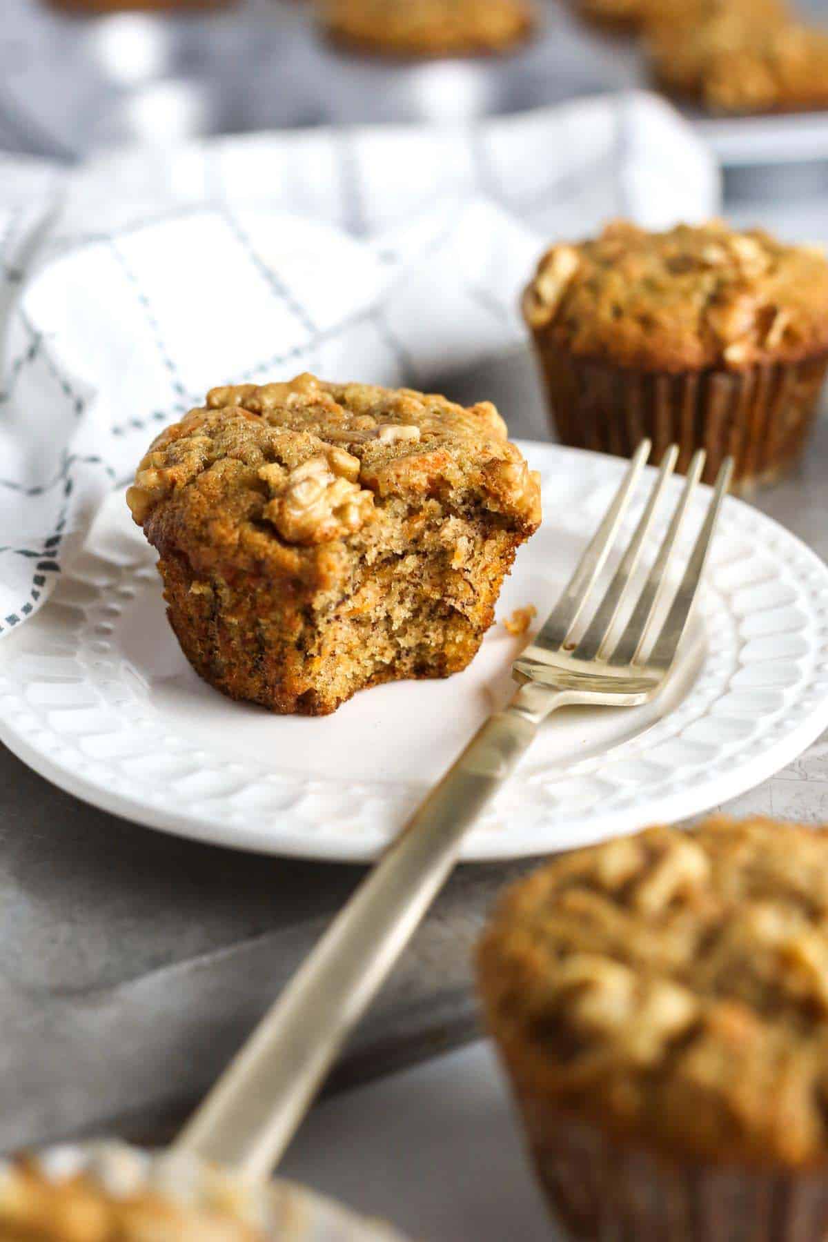 A muffin on a plate with a fork next to it.