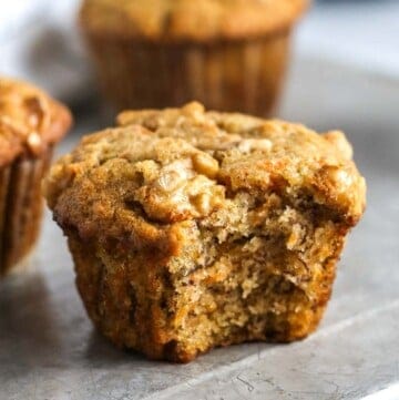 a close up of a banana carrot muffin with a bite taken out of it.