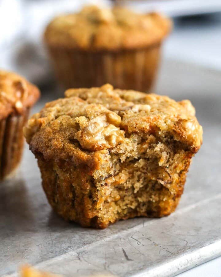 a close up of a banana carrot muffin with a bite taken out of it.