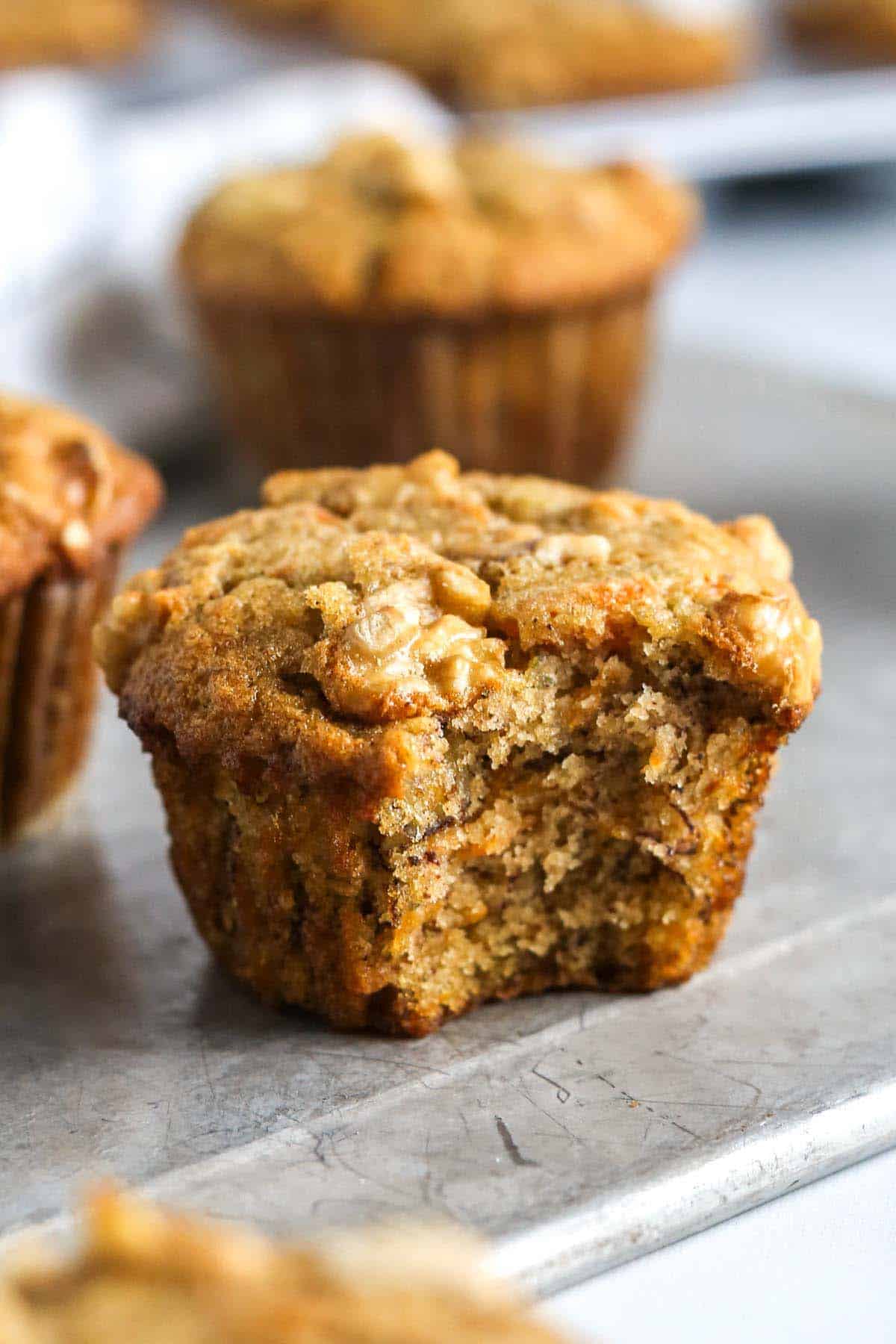a close up of a banana carrot muffin with a bite taken out of it.
